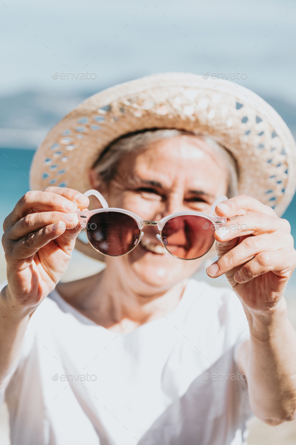 Happy Mature Woman Of 50 Years On The Beach With Trendy Sunglasses And